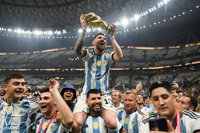 LUSAIL CITY, QATAR - DECEMBER 18: Lionel Messi of Argentina celebrates with the FIFA World Cup Qatar 2022 Winner's Trophy on Sergio 'Kun' Aguero's shoulders after the team's victory during the FIFA World Cup Qatar 2022 Final match between Argentina and France at Lusail Stadium on December 18, 2022 in Lusail City, Qatar.  (Photo by David Ramos - FIFA/FIFA via Getty Images)